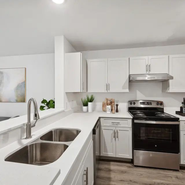 A modern kitchen with white cabinets and stainless steel appliances.